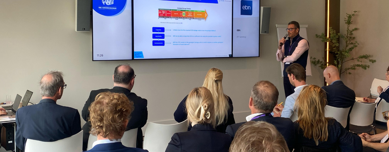 Presenter speaks beside a slide on the CCS geological storage timeline at the ZEP–EBN workshop, audience seated in a conference room.